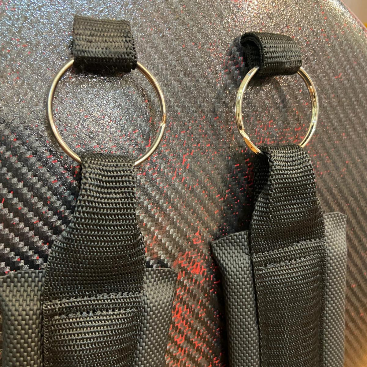 Two black backstraps with gold rings on a hard cello case